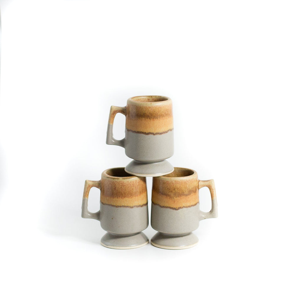 Beige and gray coffee mugs stacked on white background