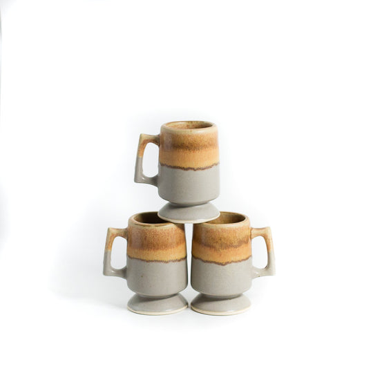 Beige and gray coffee mugs stacked on white background