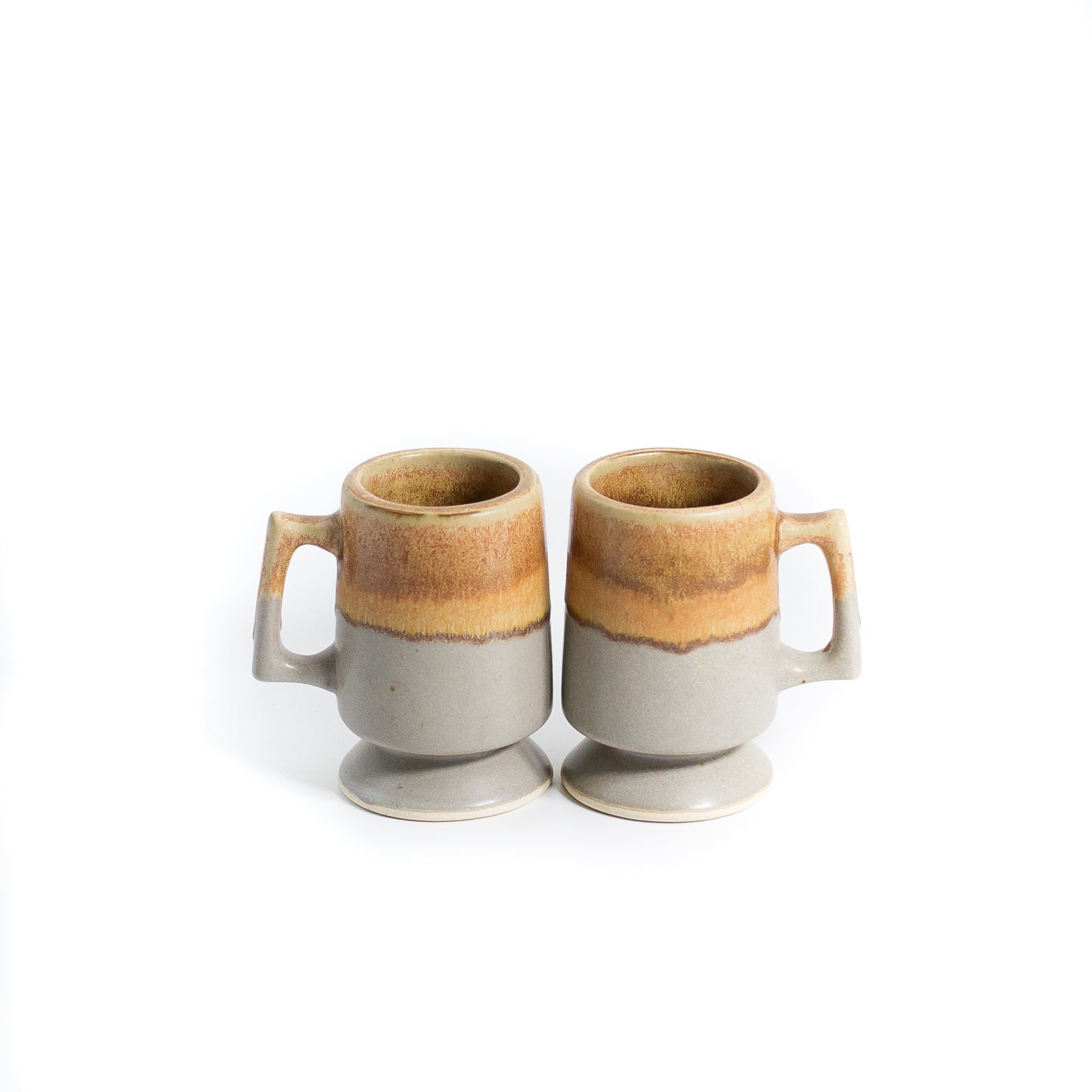 Beige and gray coffee mugs stacked on white background
