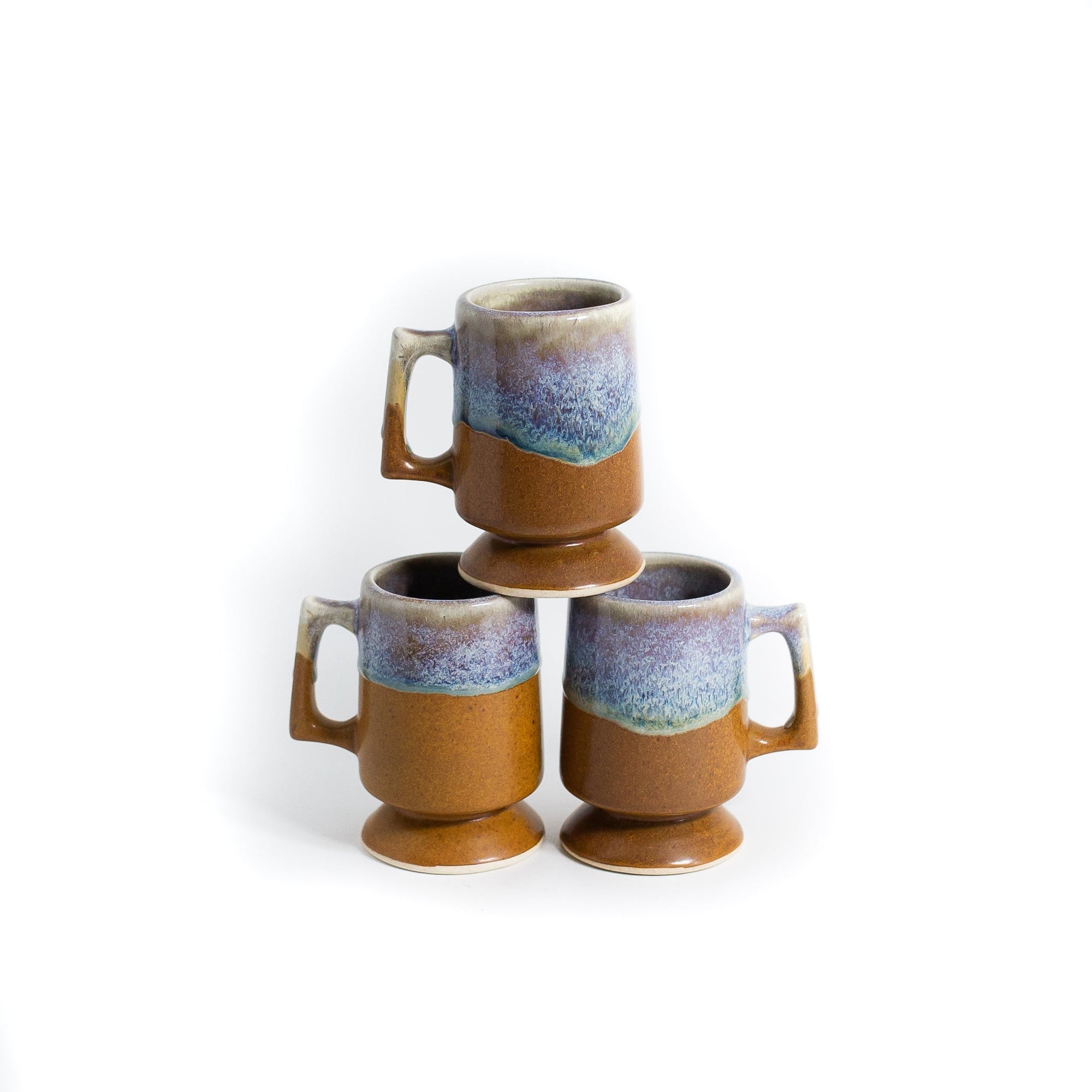 Sea and sand coloured coffee mugs stacked on white background