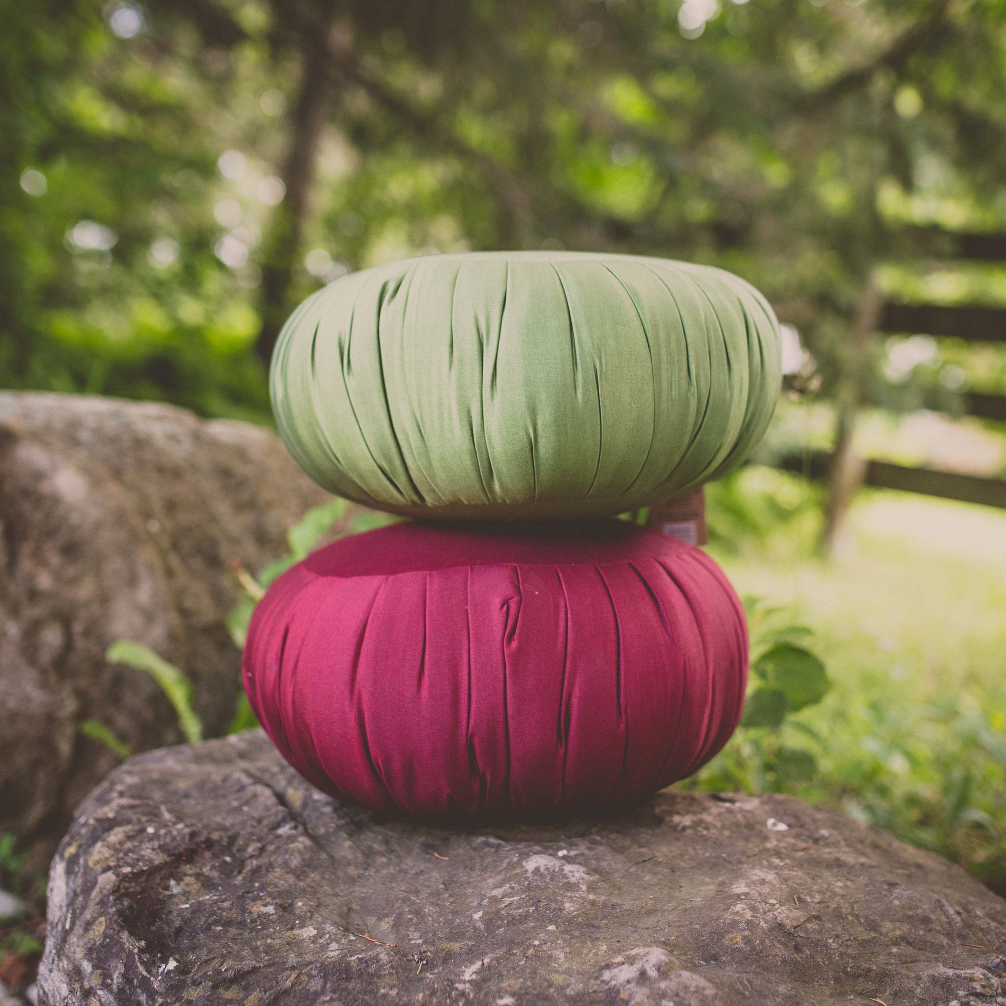 Photo of a red and a green round yoga support cushion with grassy background