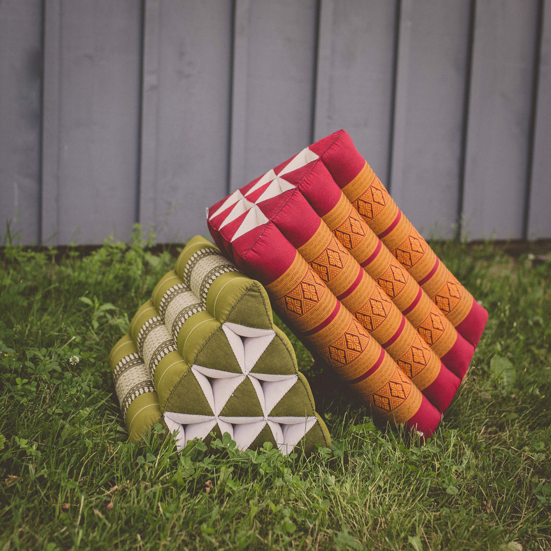 Photo of a triangular yoga support cushion with a deck or grassy background 
